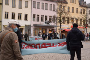 Zu sehen ist eine Kundgebung auf dem Saalfelder Markt und ein Transparent mit der Aufschrift "Mundnasenschutz tragen ist keine Diktatur"